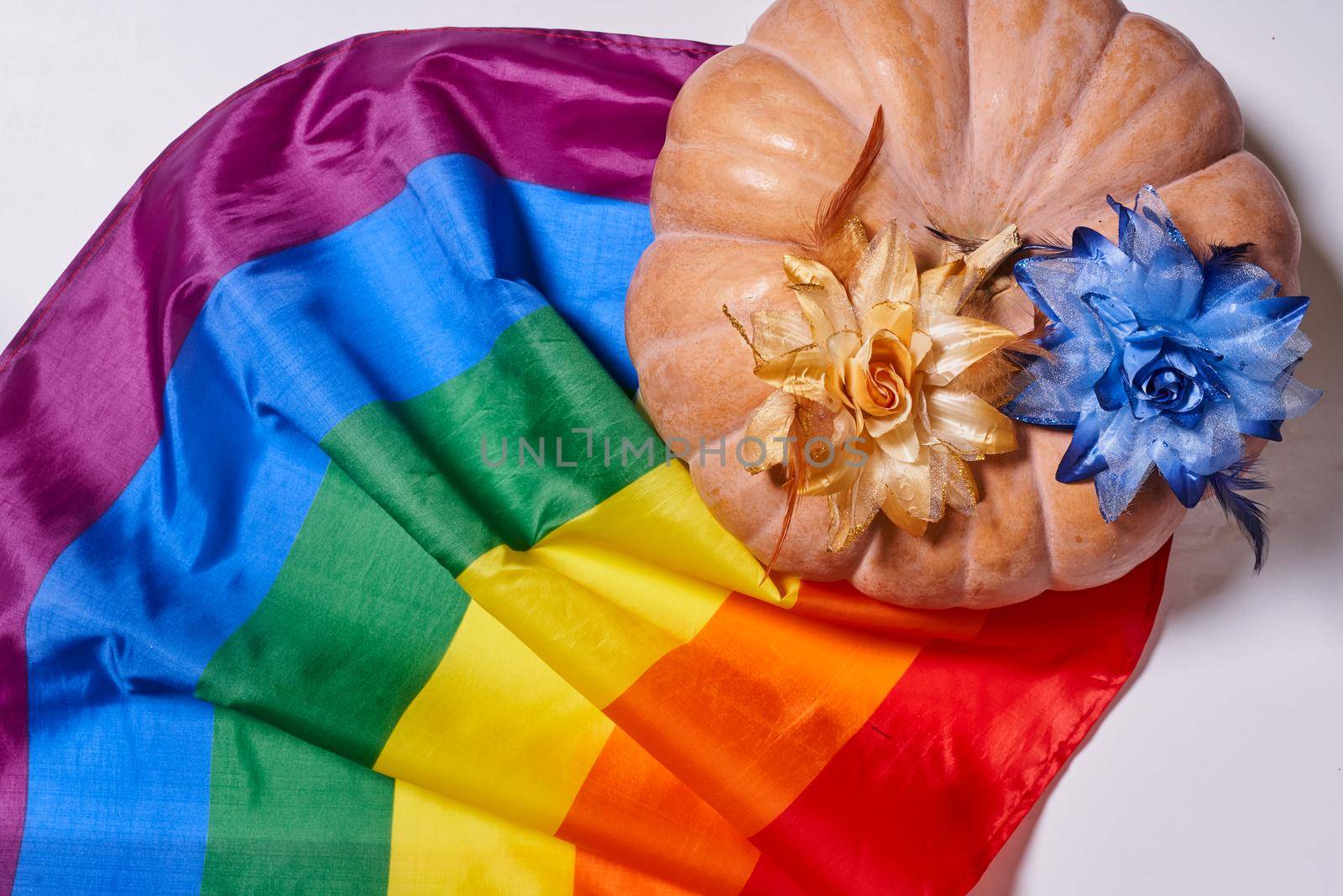 LGBTQ rainbow flag and big orange pumpkin. Halloween pumpkin with rainbow LGBT flag