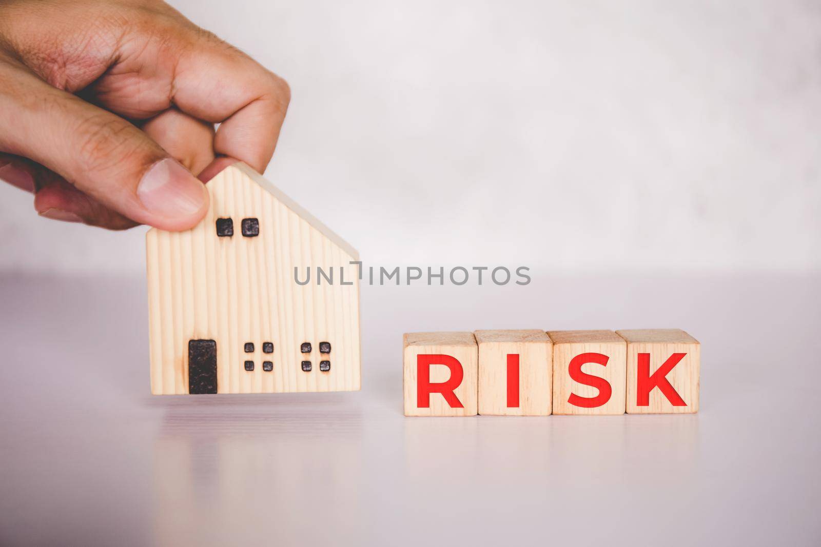 Planning with finance and investment of business about real estate with risk and safety of insurance, uncertainty for economy, hands put home and cube wooden block with word RISK, business concepts. by nnudoo