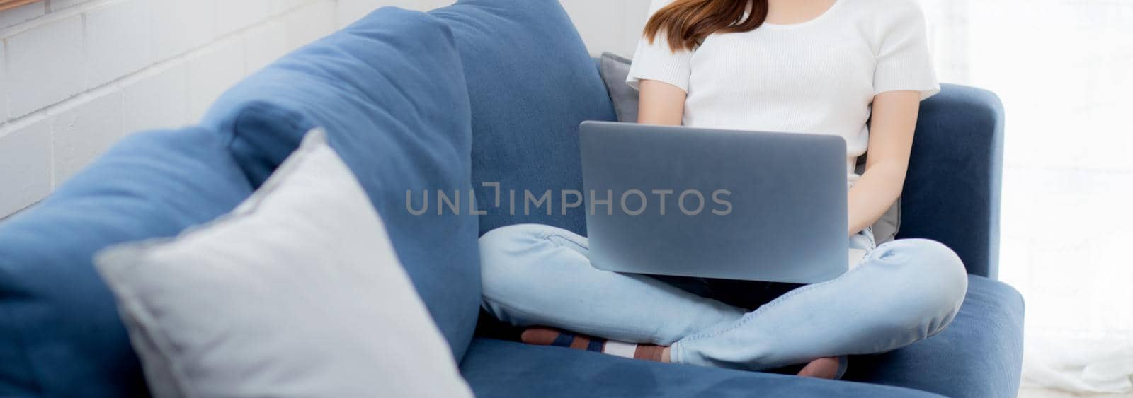 Young asian business woman in face mask work from home on laptop computer online to internet in living room, girl in medical mask and quarantine for pandemic of covid-19, stay home, new normal.