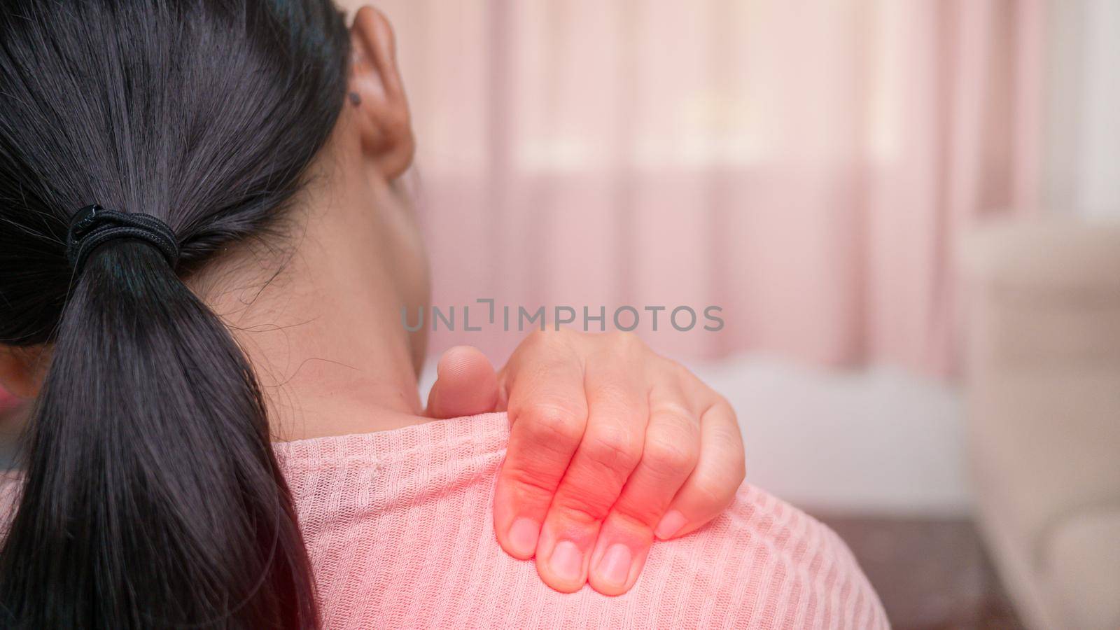Close up of female massaging her painful shoulder caused by prolonged work on the computer or phone. Neck, trapezoid and shoulders pain. Muscle spasm.