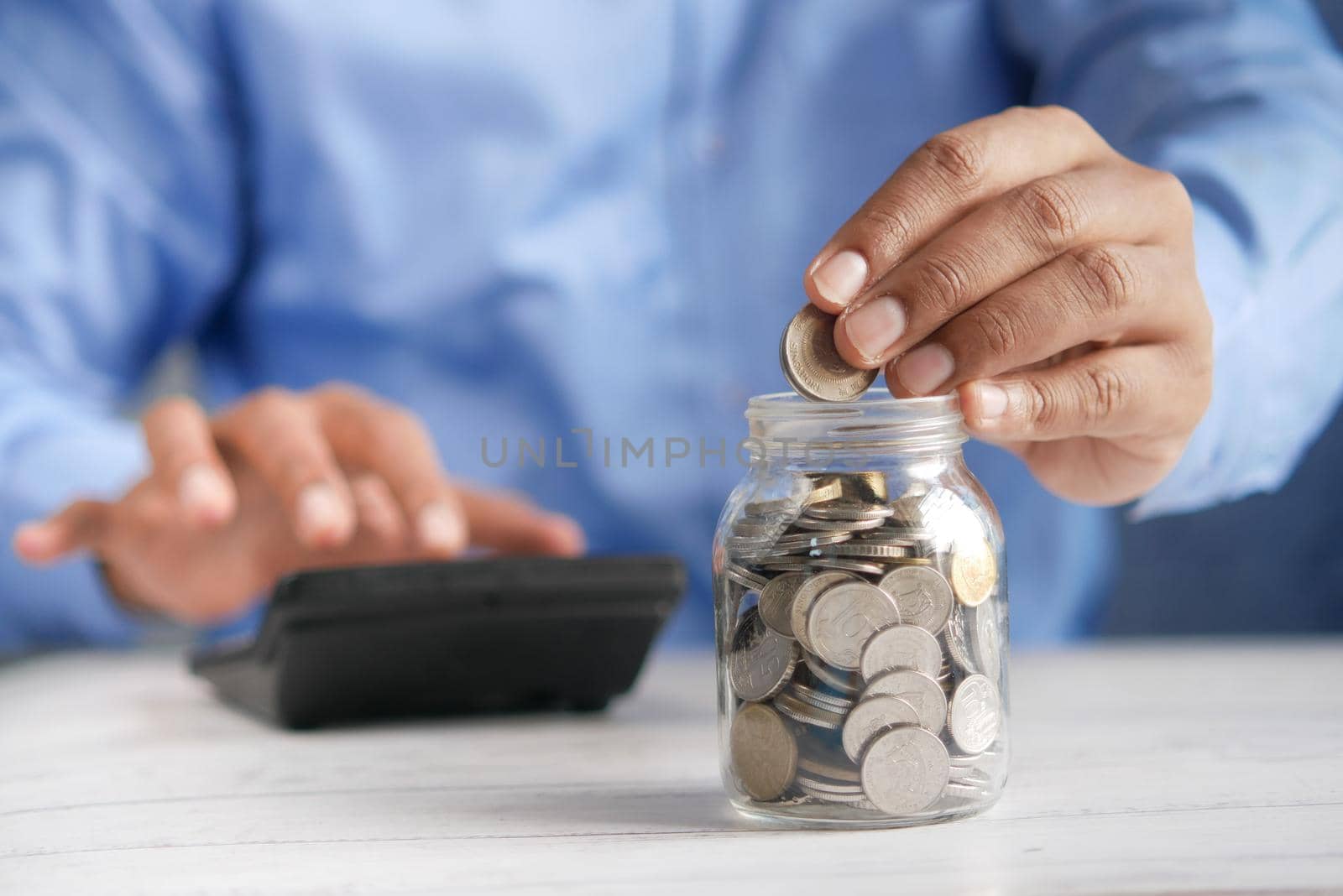 young man saving coins in a jar white sited .