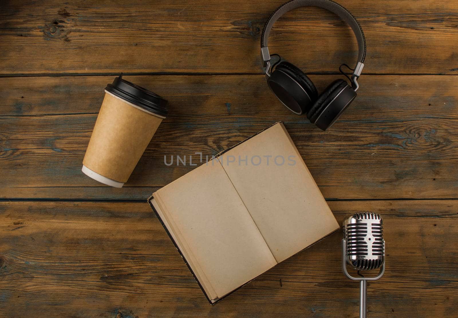Open book with blank page, headphone and a cup of coffee in a disposable paper cup on a wooden table. Remote education concept. Top view