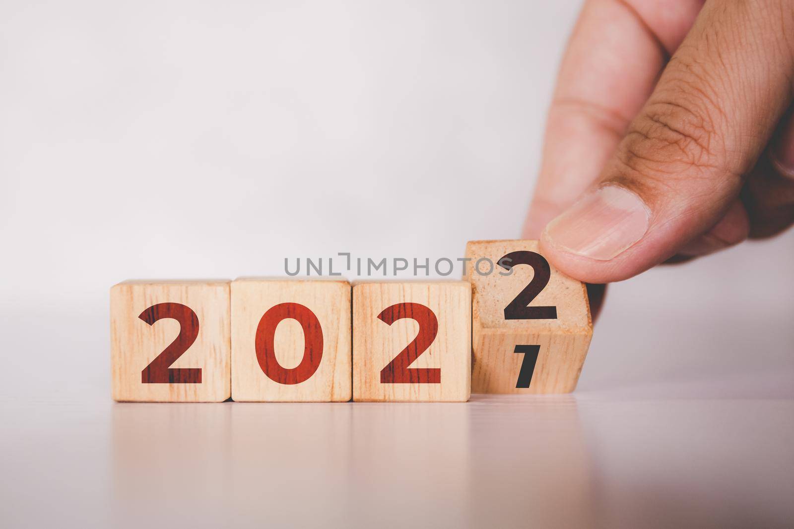 Hands flipping cube wooden block with text year 2022, beginning and trend, calendar and time, determination target and planning for achievement, motivation and aspirations, business concepts.