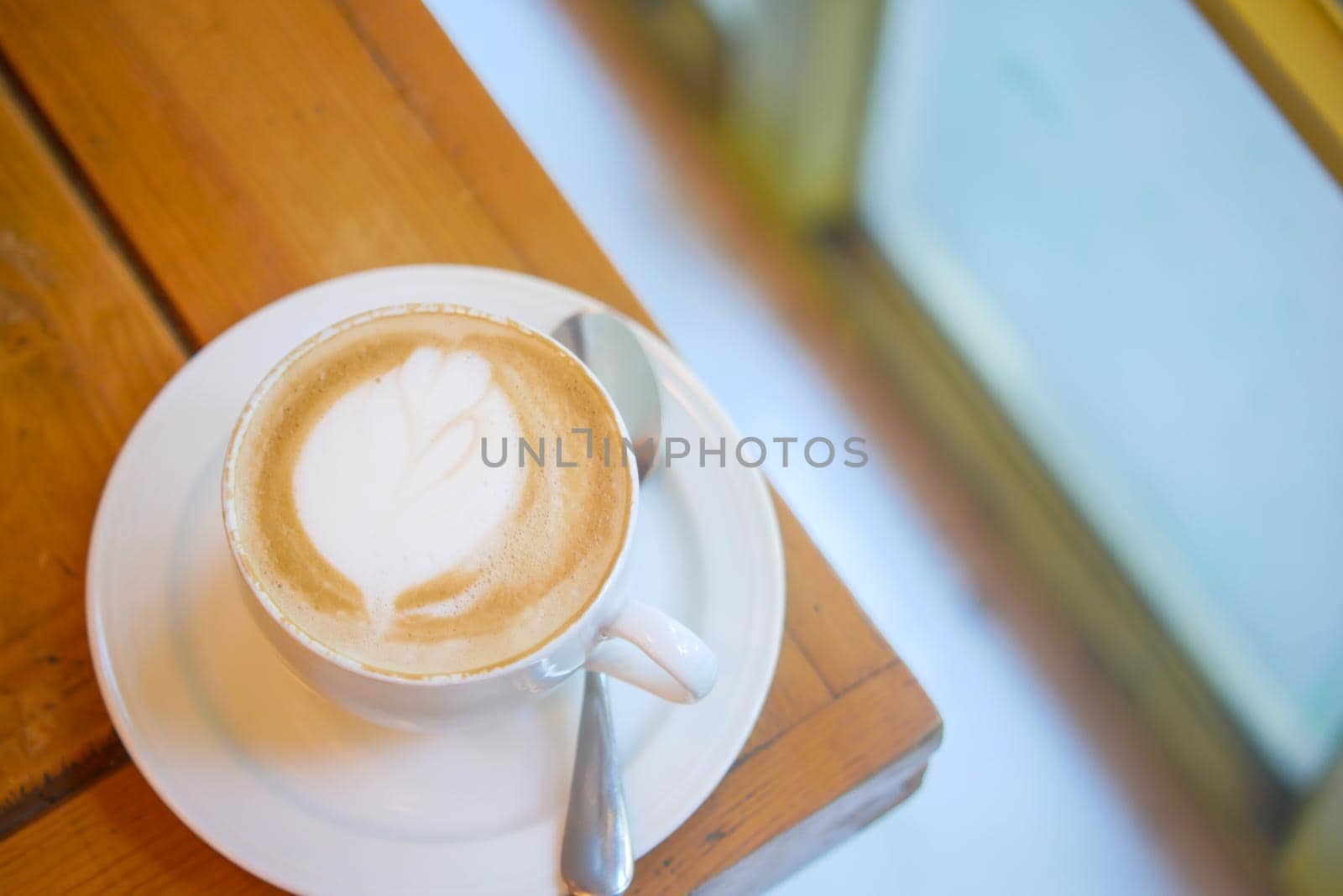 a cup of late coffee with flower shape design on top at cafe .