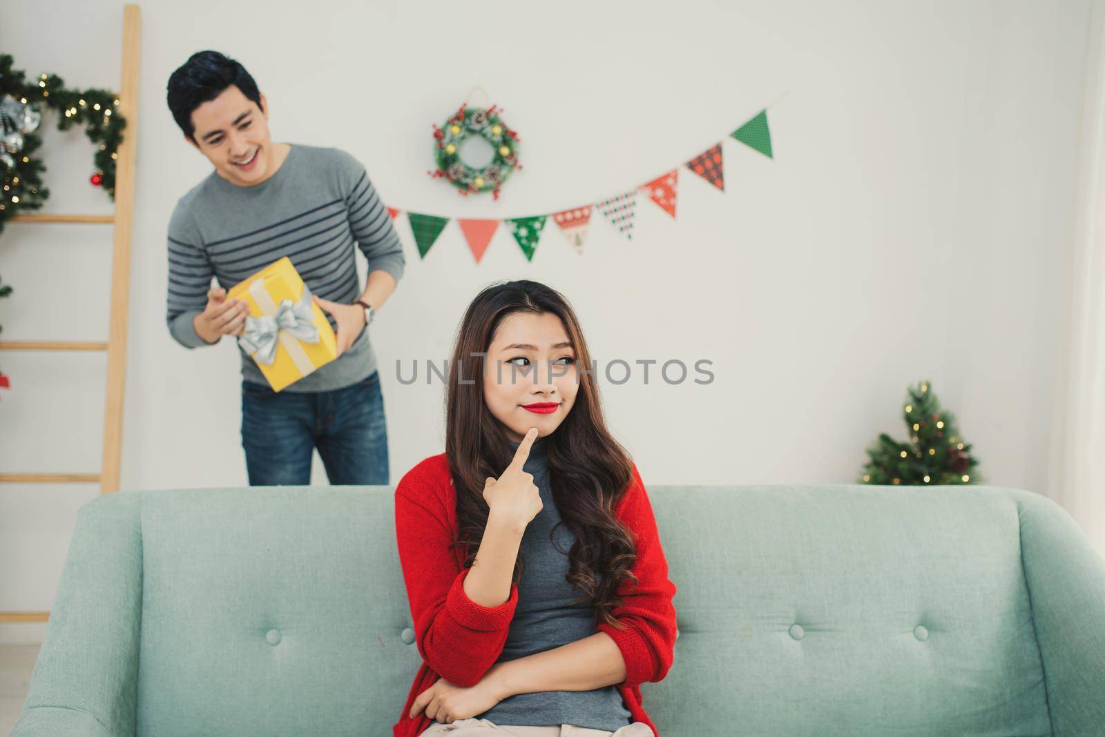 Christmas Asian Couple. A handsome man giving her girlfriend/wife a gift at home celebrating New Year People by makidotvn