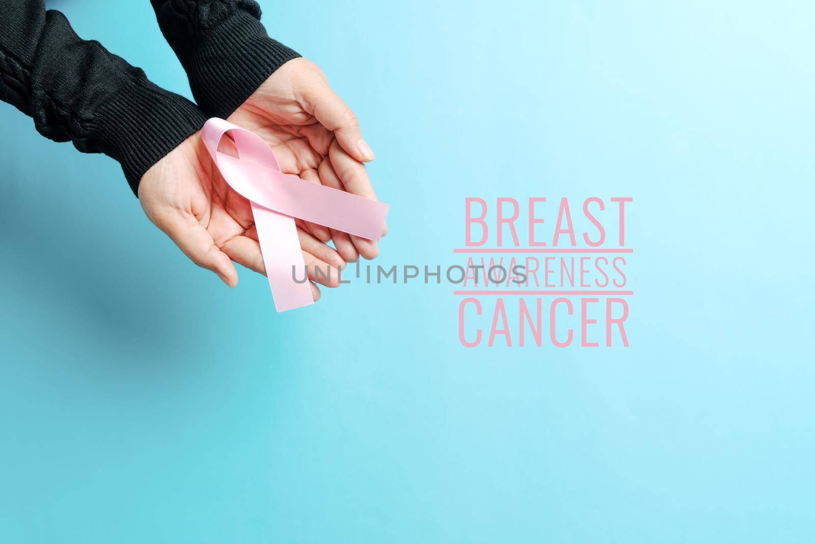 pink badge ribbon on woman hand to support breast cancer cause. breast cancer awareness concept by psodaz