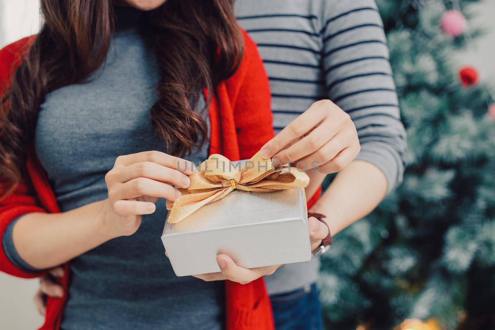 Christmas Asian Couple. A handsome man giving her girlfriend/wife a gift at home celebrating New Year People by makidotvn