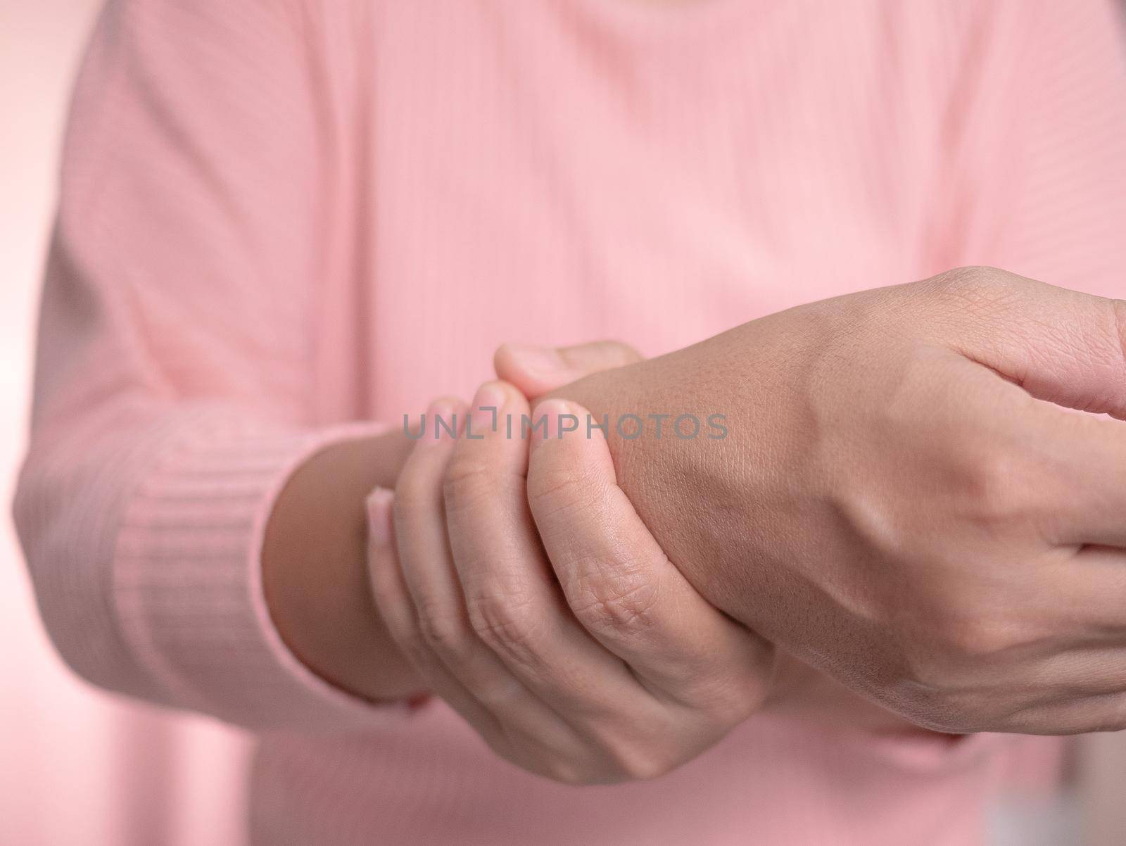 Closeup of female holding her painful wrist caused by prolonged work on the computer or housewife, Carpal tunnel syndrome, arthritis. Neurological disease concept. by TEERASAK