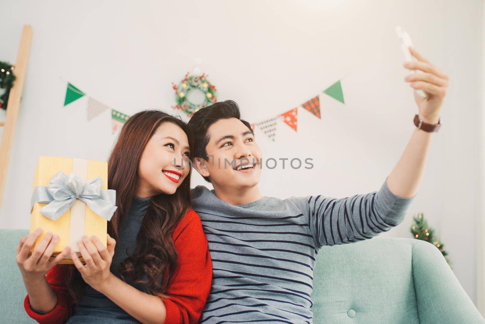 Christmas Asian Couple. A handsome man giving her girlfriend/wife a gift at home celebrating New Year People by makidotvn