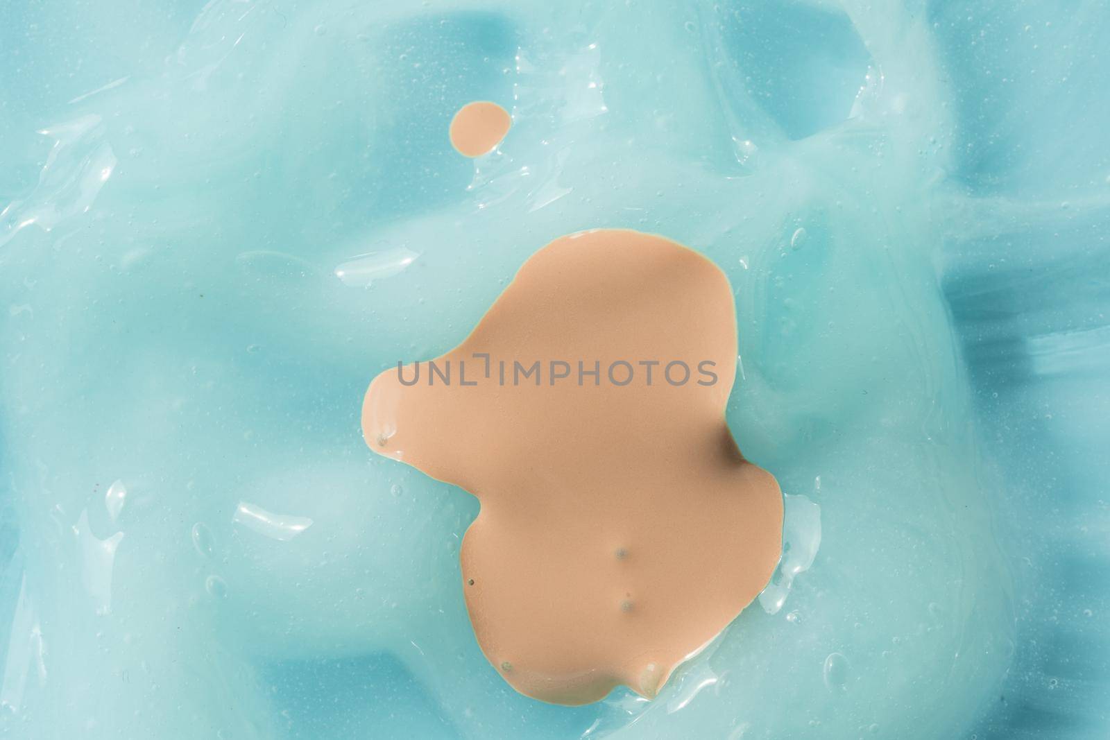 Liquid foundation smear on blue cream textured background. Creamy skincare lotion mousse product closeup. Shampoo texture, sunscreen cosmetic smear background. Moisturizing beauty creme swatch.