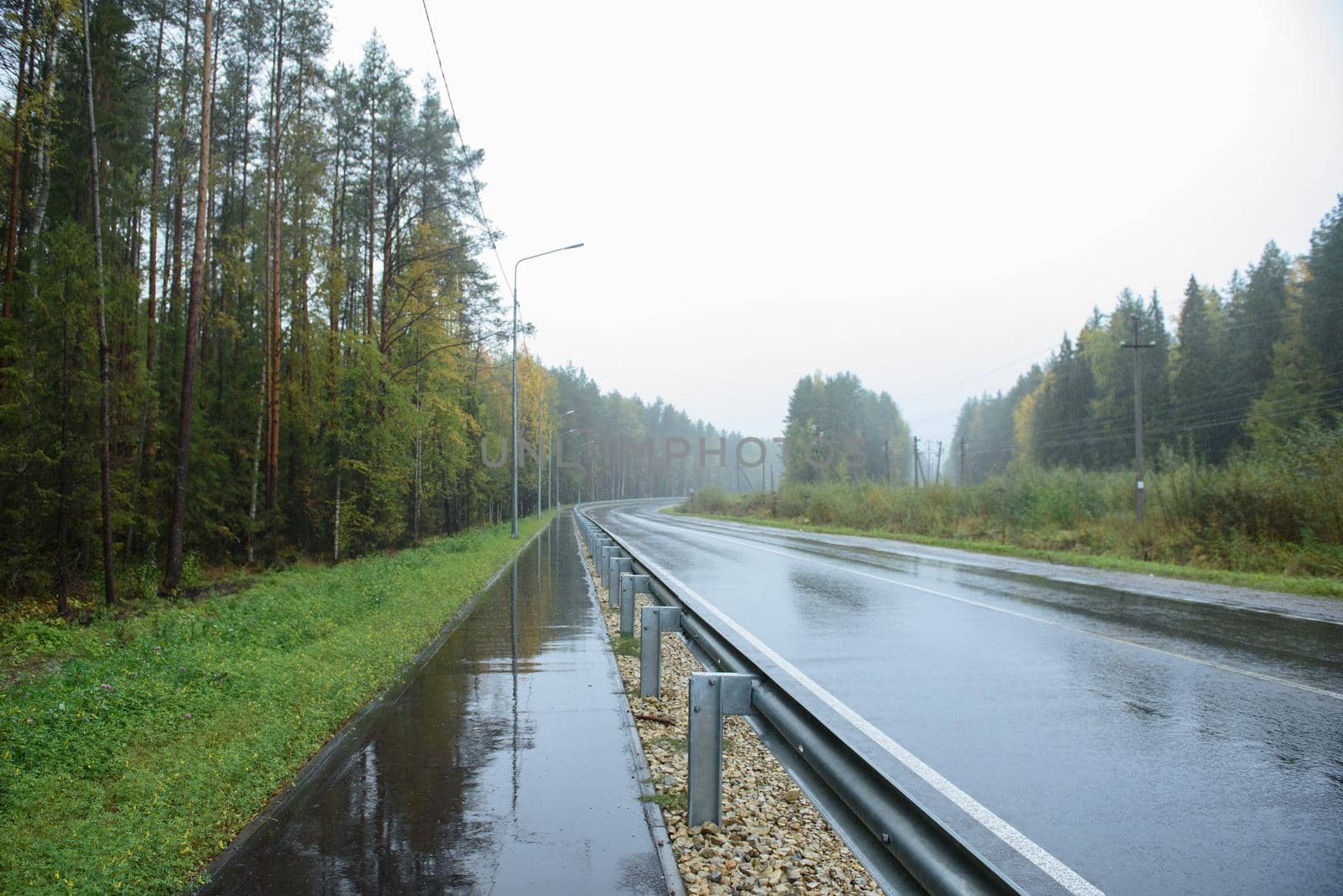 A road section with a pedestrian path located along it by rainy weather