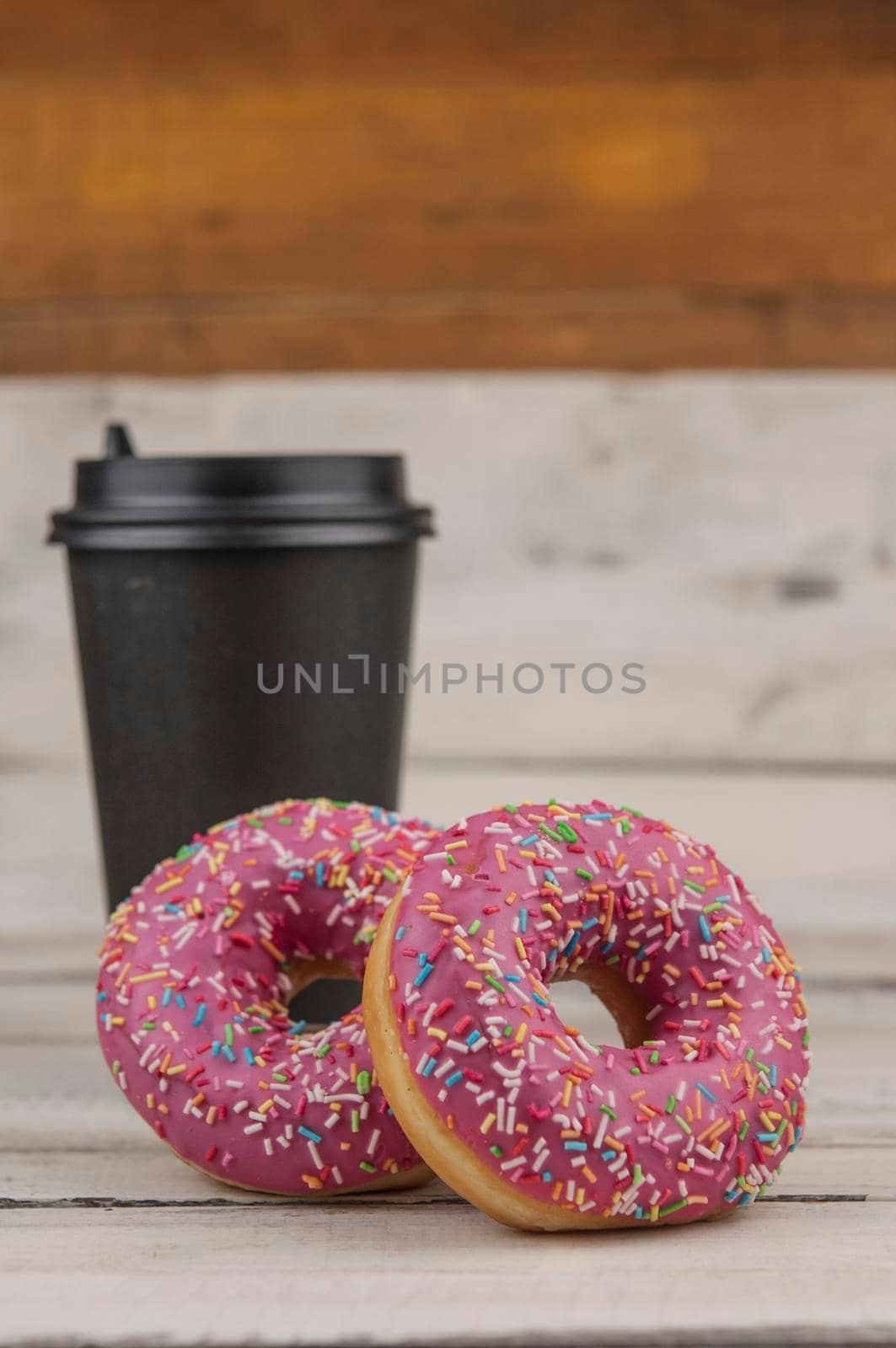 colorful donuts  and  disposable cup of coffee on a wooden table. Photo of sweecolorful donuts  and  disposable cup of coffee on a wooden table. Photo of sweets. Copy space. ts. Copy space. Mock-up