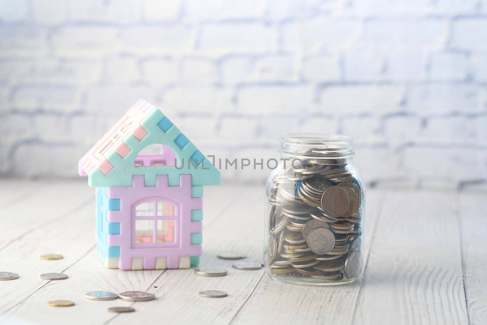coins in a jar and house on table , the concept of house finance .