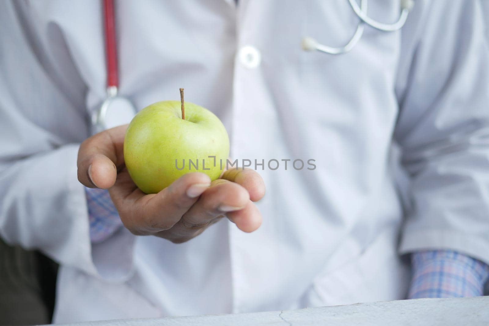doctor's hand holding green apple while sited ,