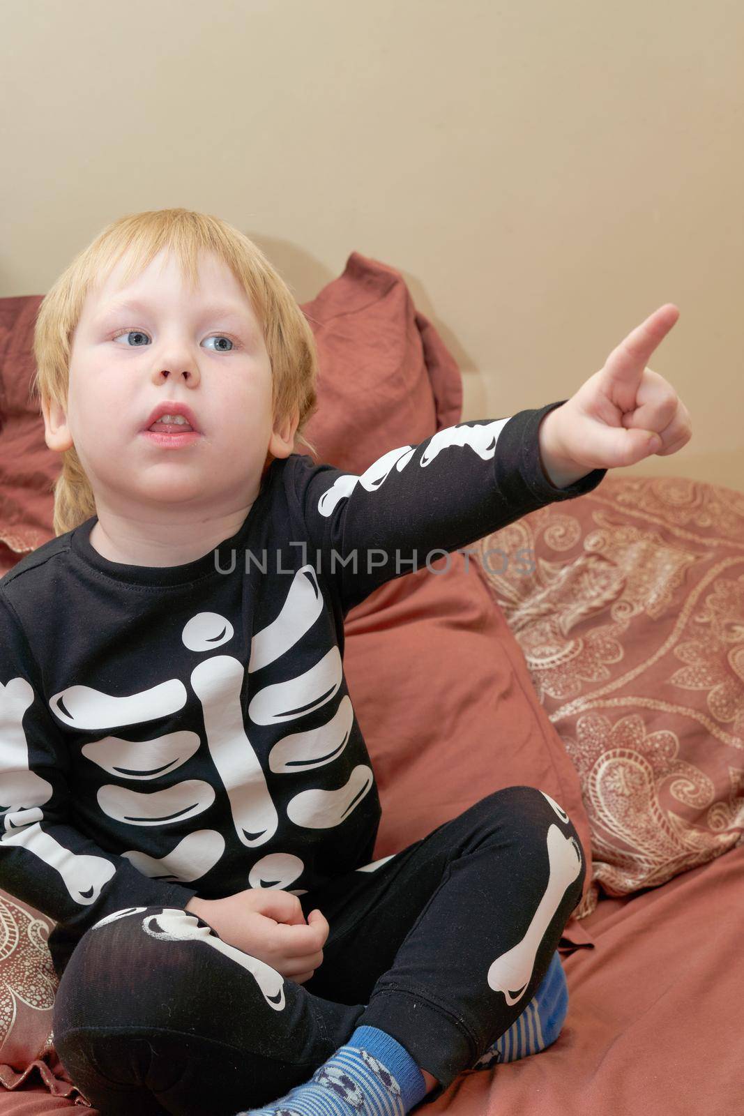 A child in a skeleton costume sits on the couch and points his finger forward by vizland