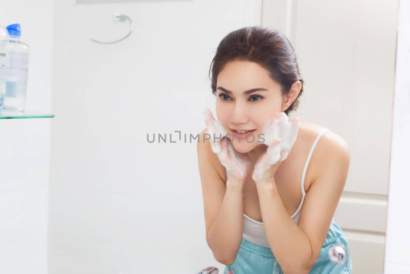 Woman happy cleanses the skin with foam in bathroom. by jayzynism
