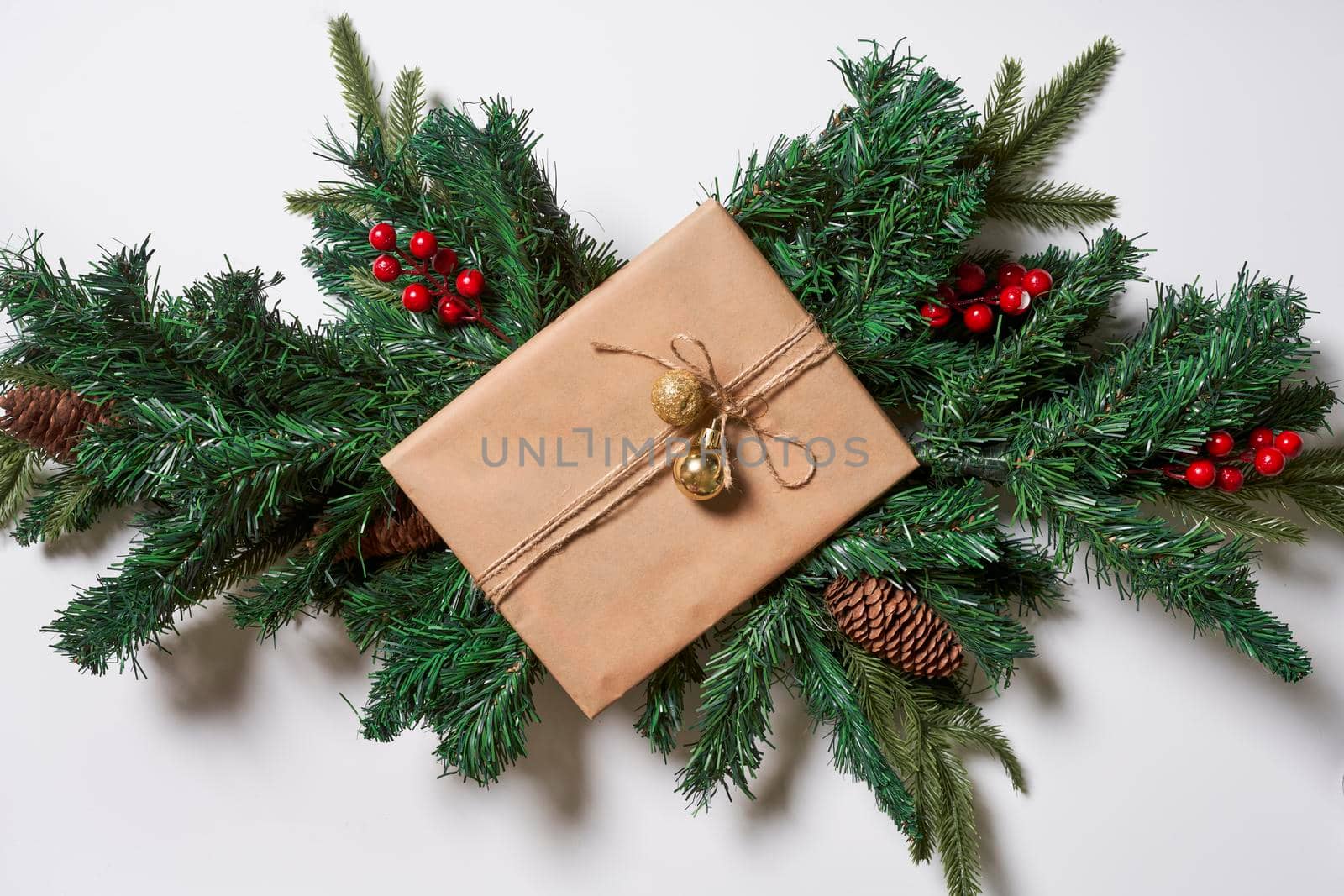 Branches of spruce tree with pine cones and Christmas toy decorations on white background. Top view. Copy space