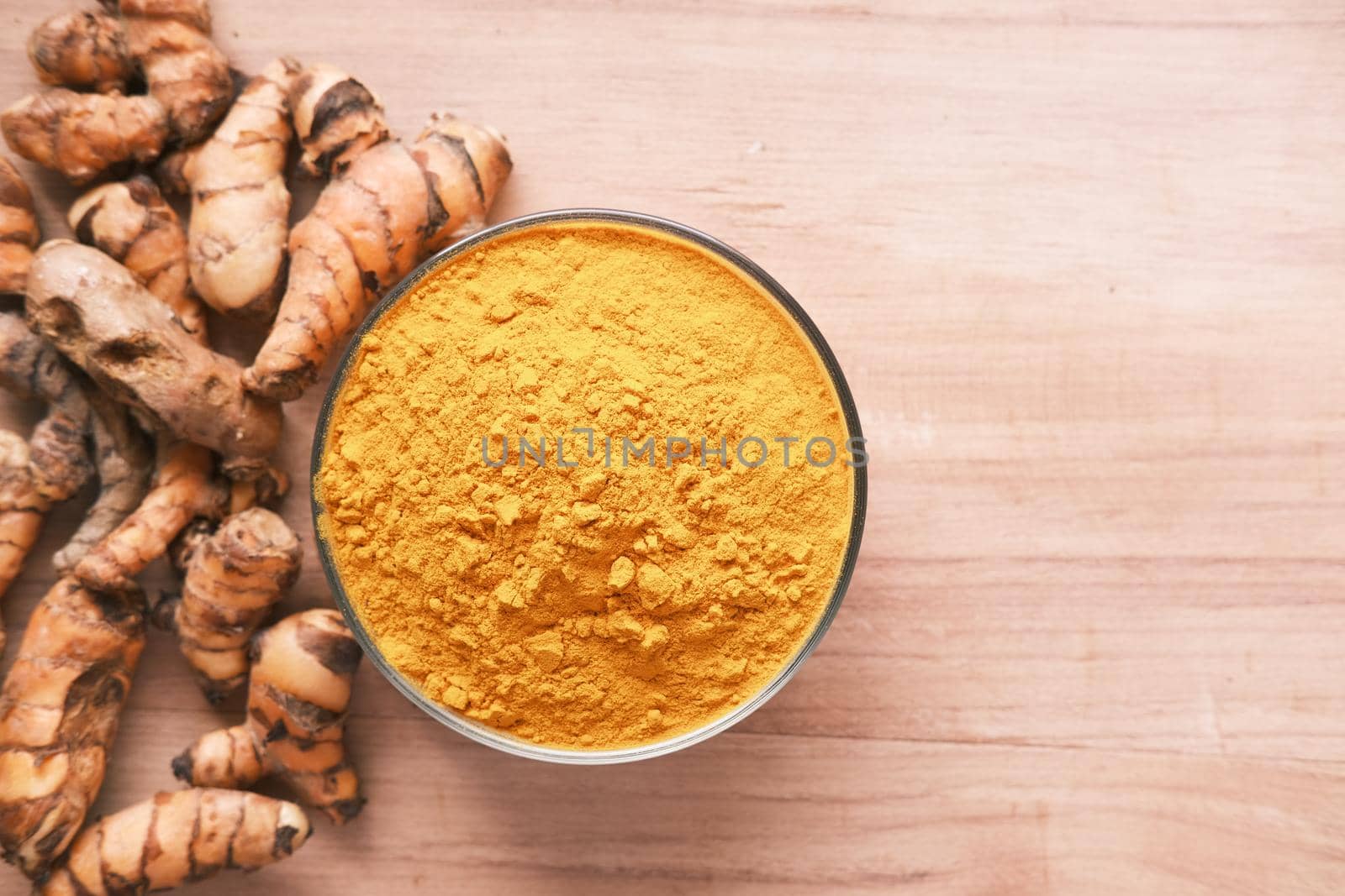 turmeric root and powder in bowl on table , top view