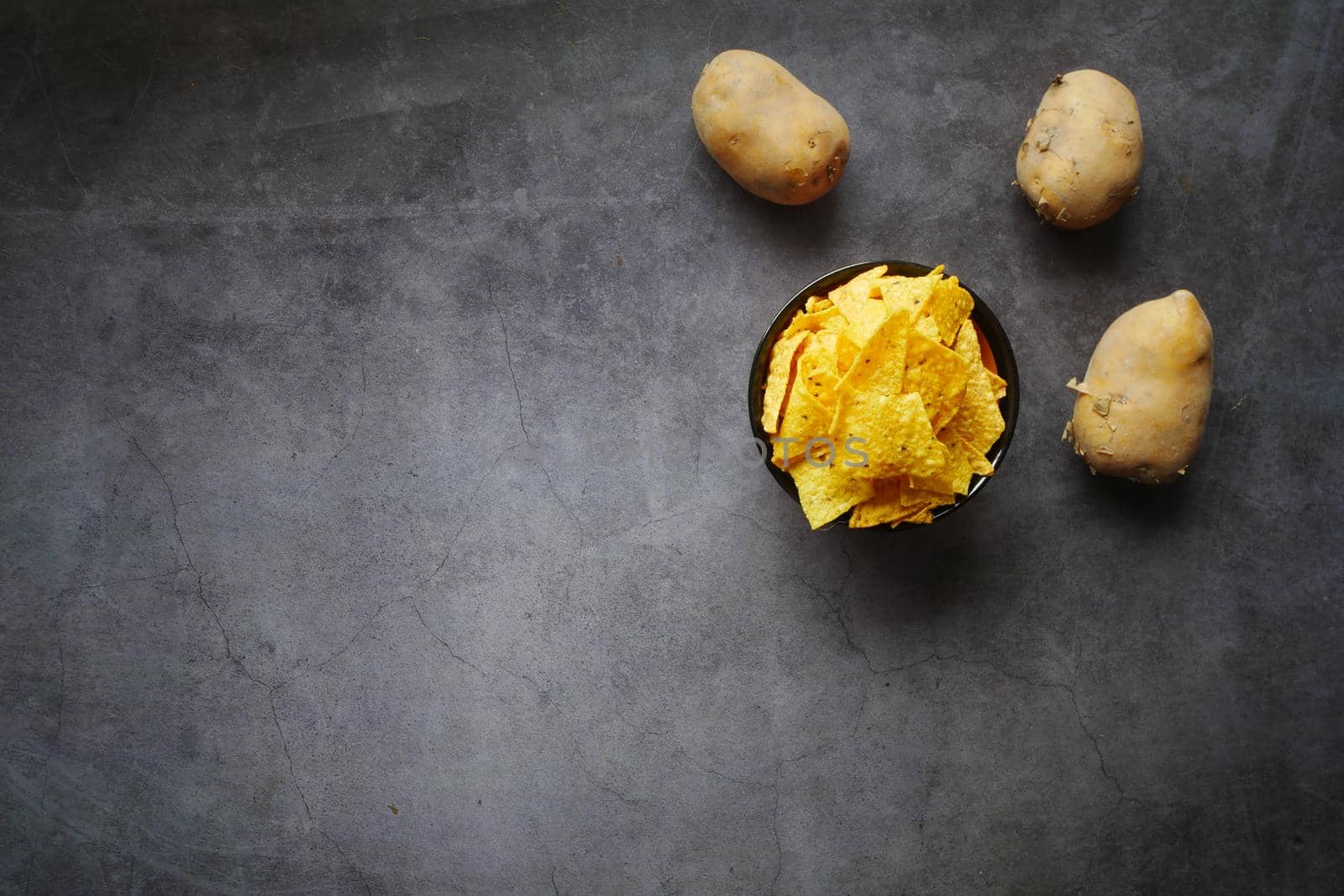 Bowl with tasty potato chips on wooden background