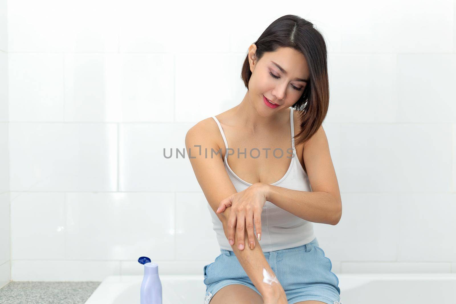 Young woman applying body lotion cream after bath. by jayzynism