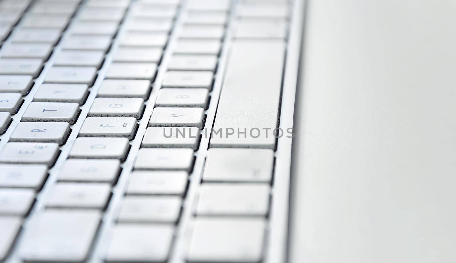 Detail of a modern white computer keyboard dirty and dusty on a white table. Computer hardware device. Technology and internet