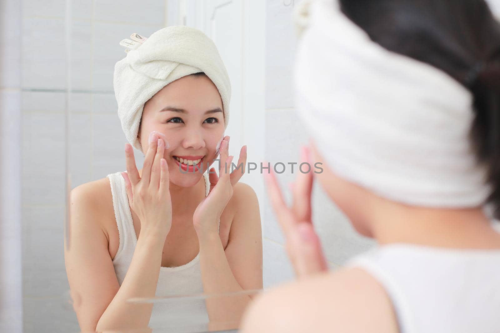 Woman happy cleanses the skin with foam on sink. by jayzynism
