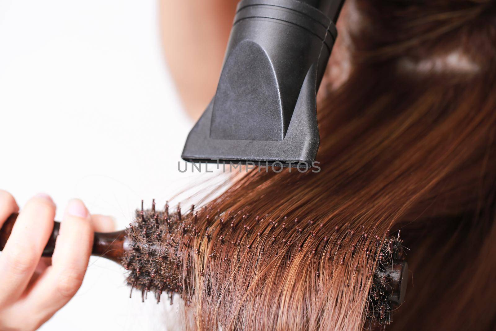 Beautiful young woman is using a hair dryer.