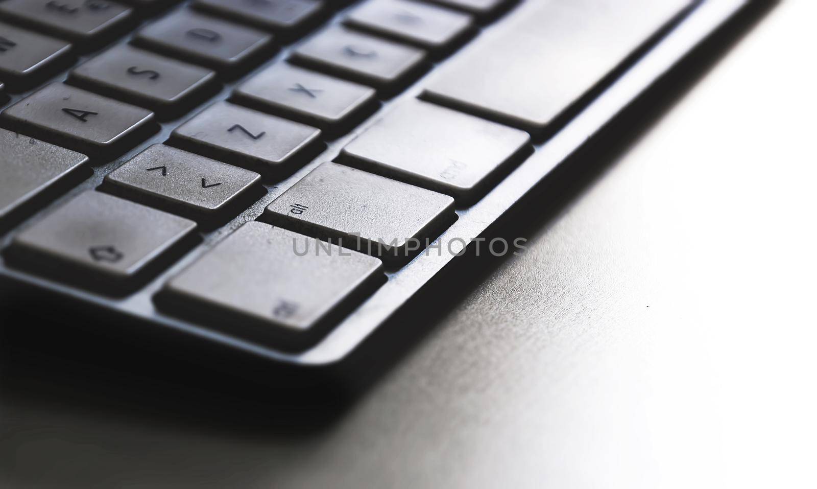 Detail of a modern white computer keyboard dirty and dusty on a white table. Computer hardware device. Technology and internet