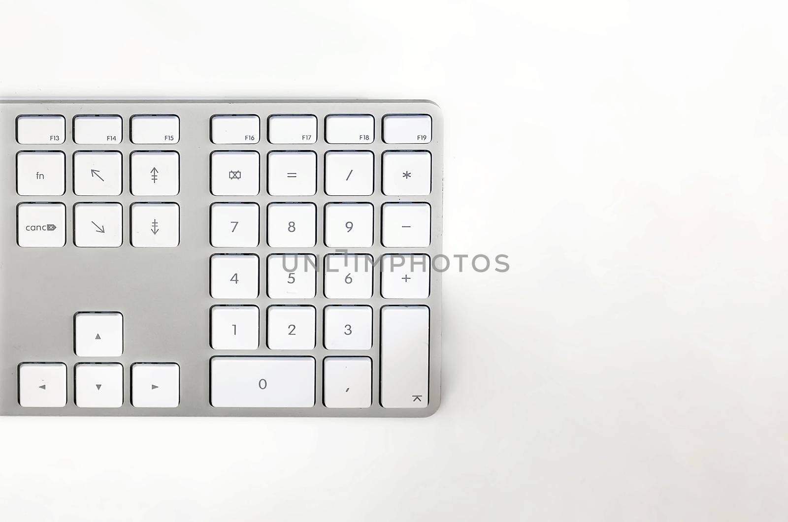 Detail of a modern white computer keyboard on a white table. Computer hardware device. Technology and internet