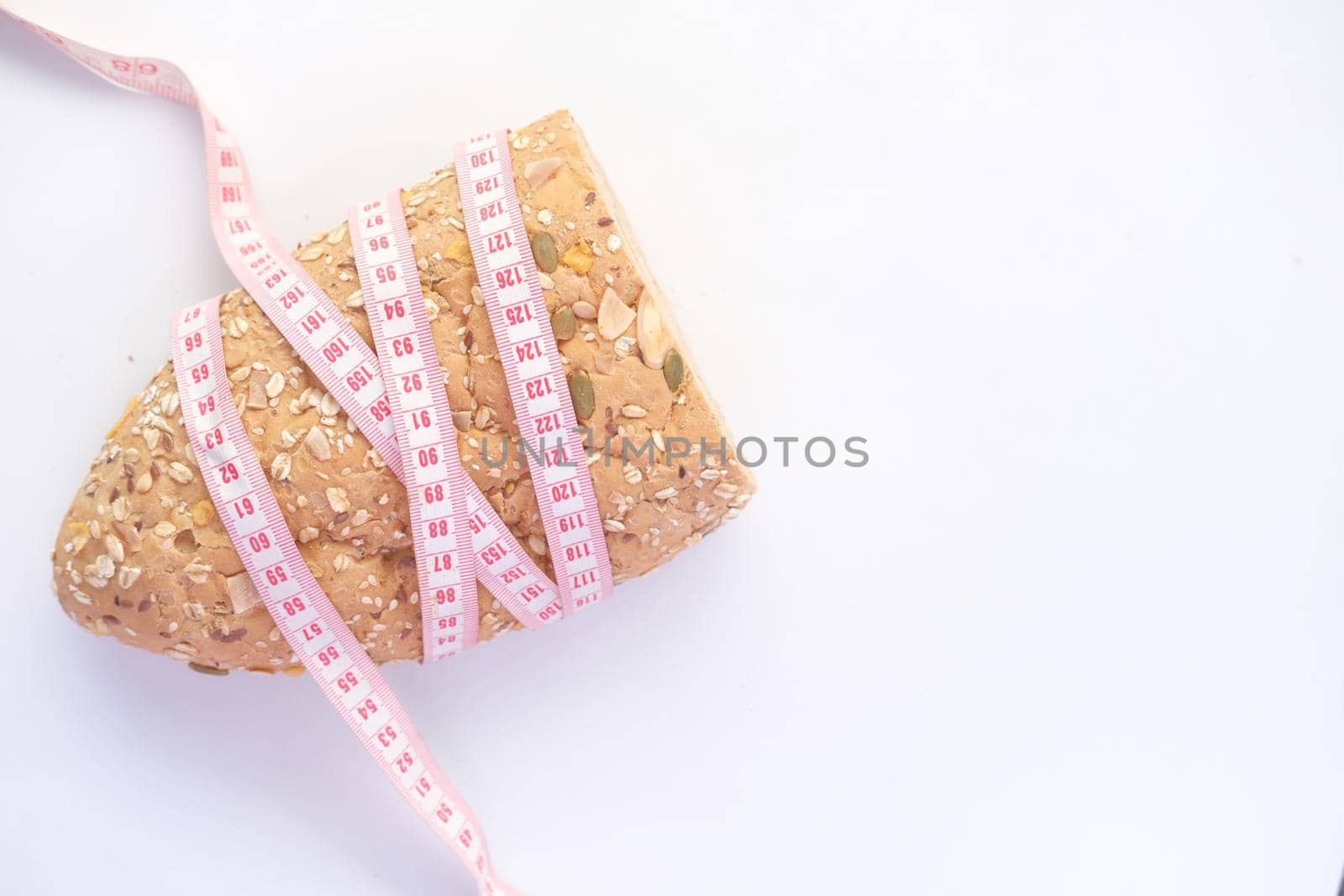 slice of whole meal bread and measurement tape on white background
