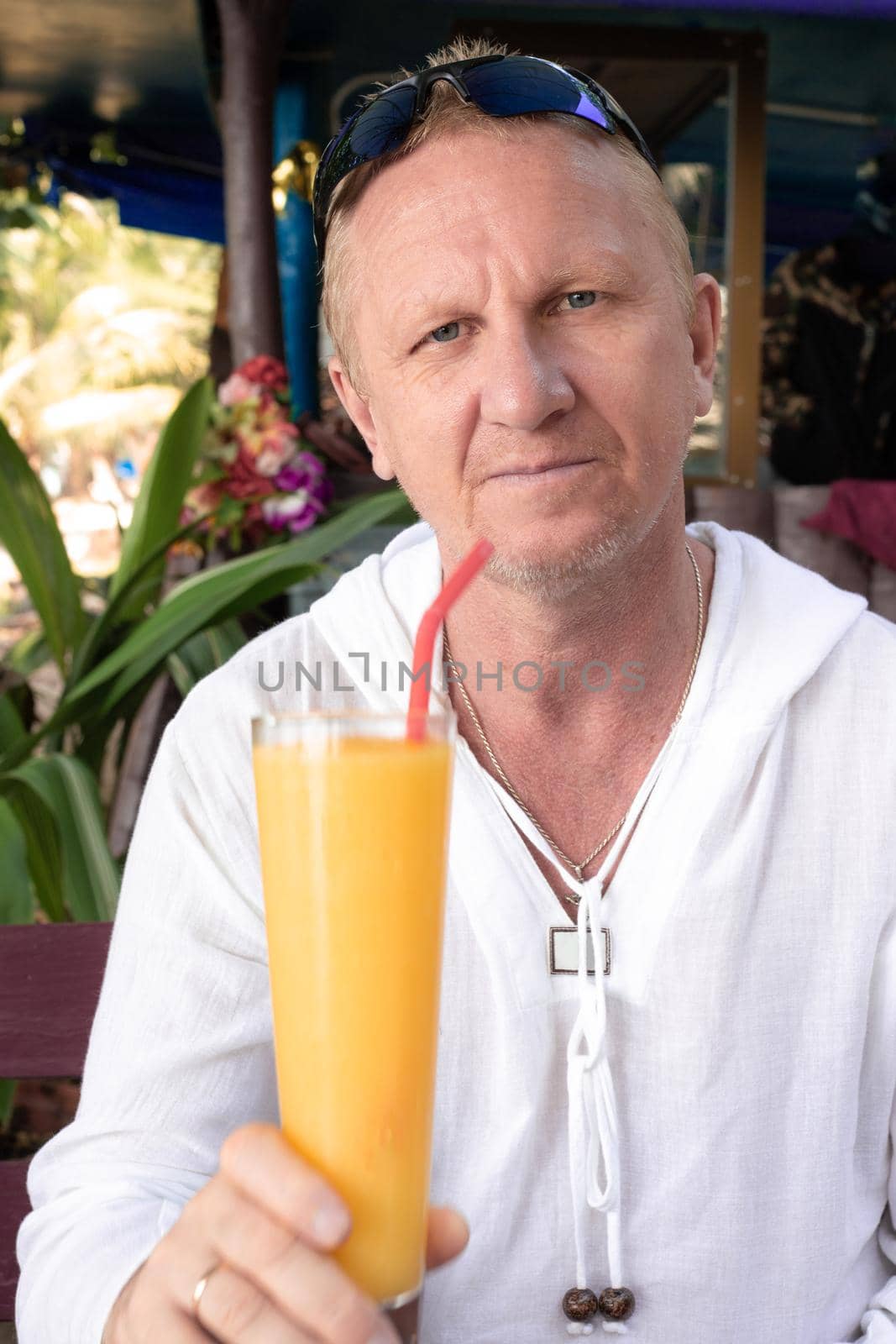 mature european man sitting in cafe with mango cocktail