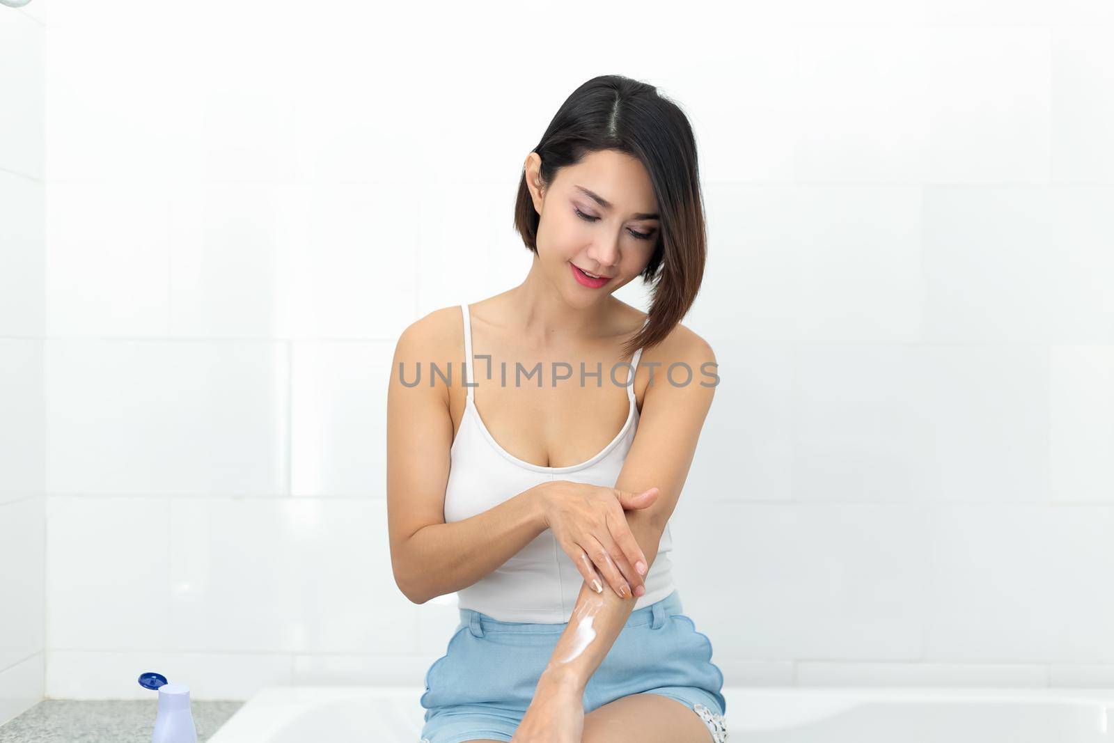 Young woman applying body lotion cream after bath. by jayzynism