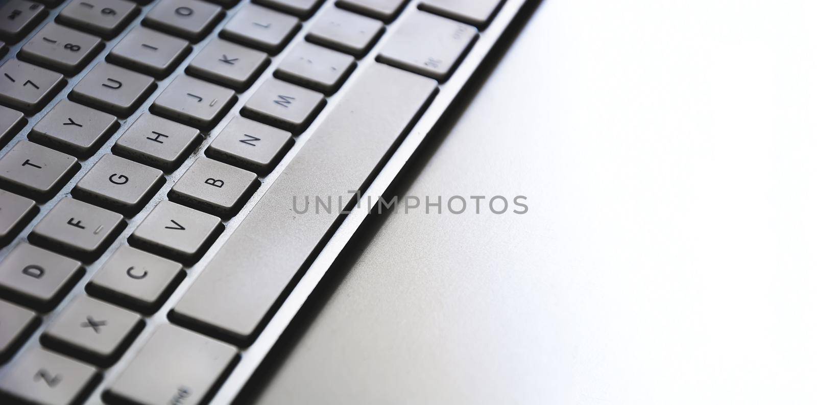 Detail of a modern white computer keyboard dirty and dusty on a white table by rarrarorro