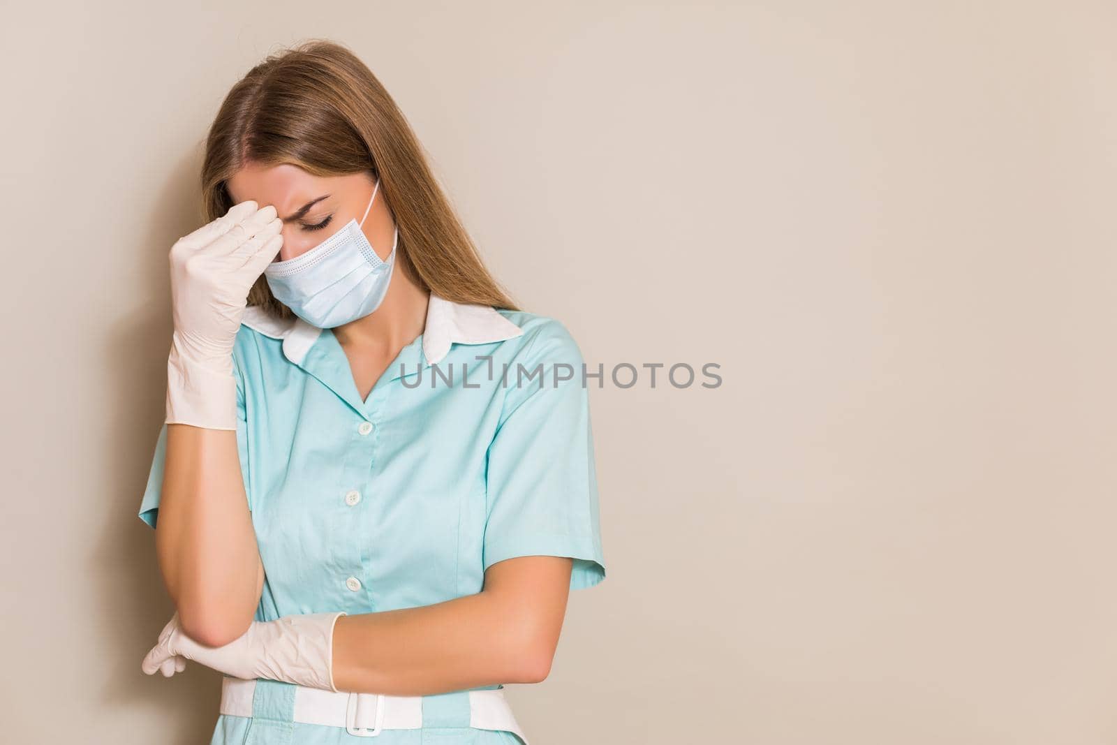 Tired nurse  with protective mask and gloves having headache.