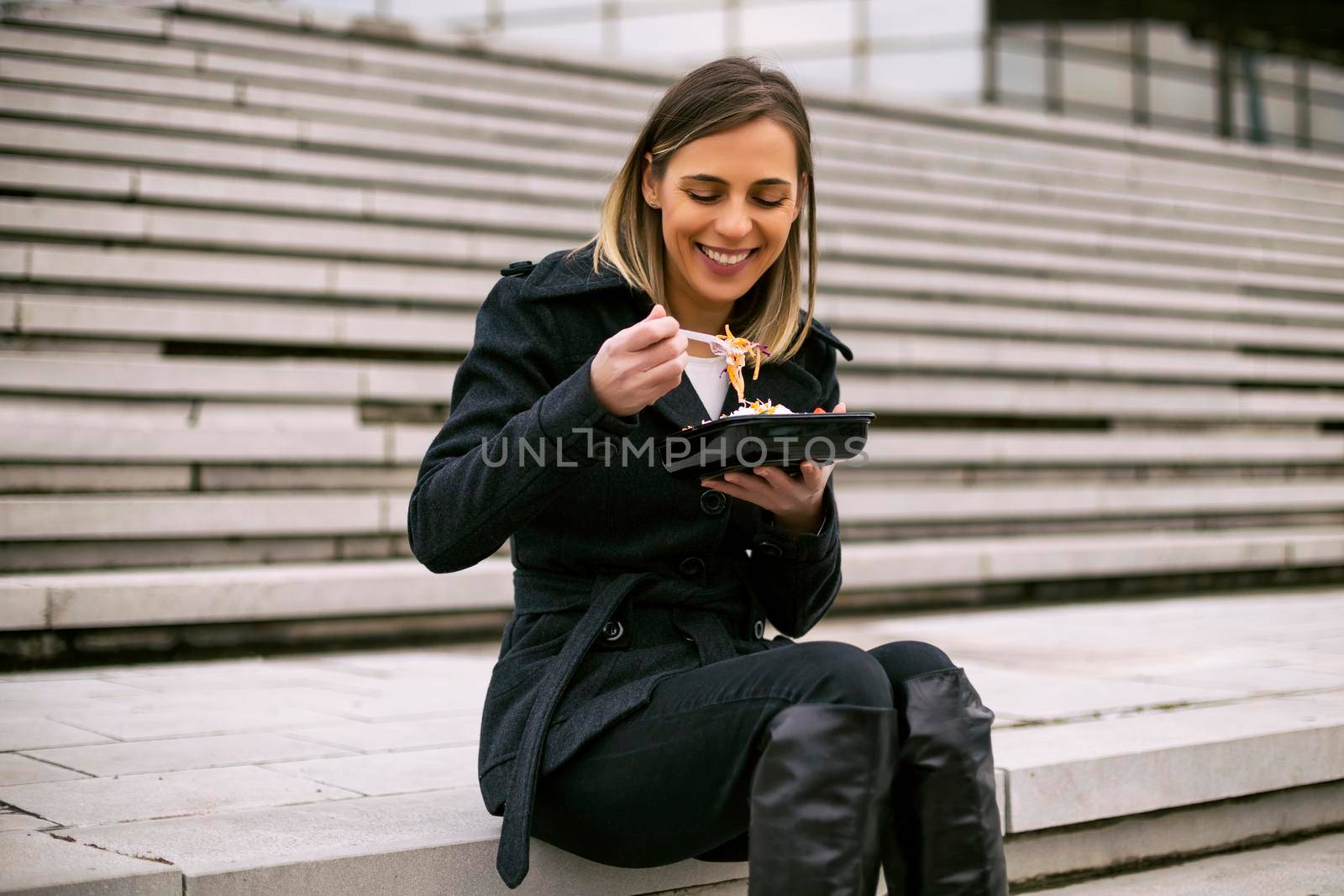 Beautiful businesswoman enjoys resting on a lunch break while sitting on the staircase in the city.