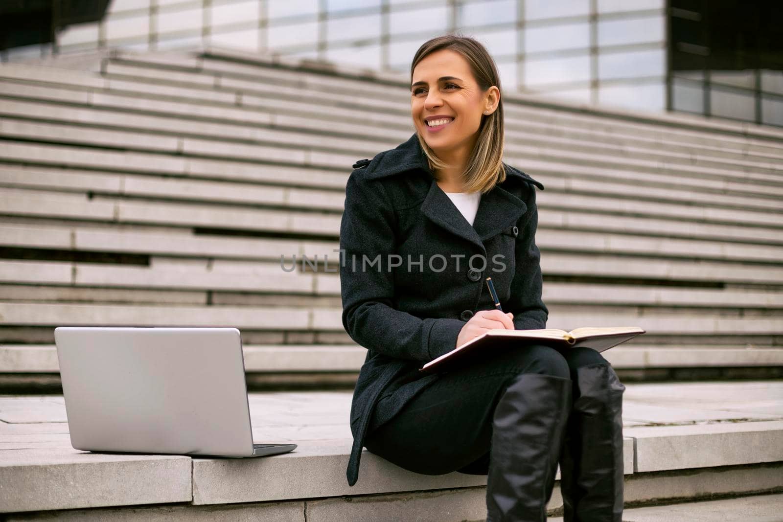 Businesswoman sitting on the staircase in the city and working by Bazdar