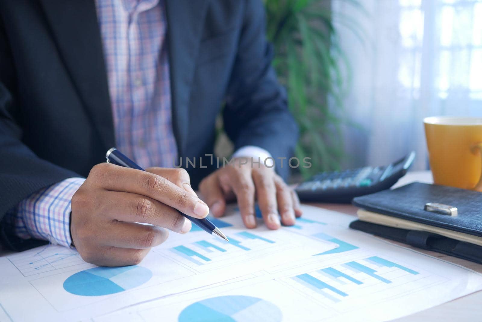 man hand with pen analyzing bar chart on paper.