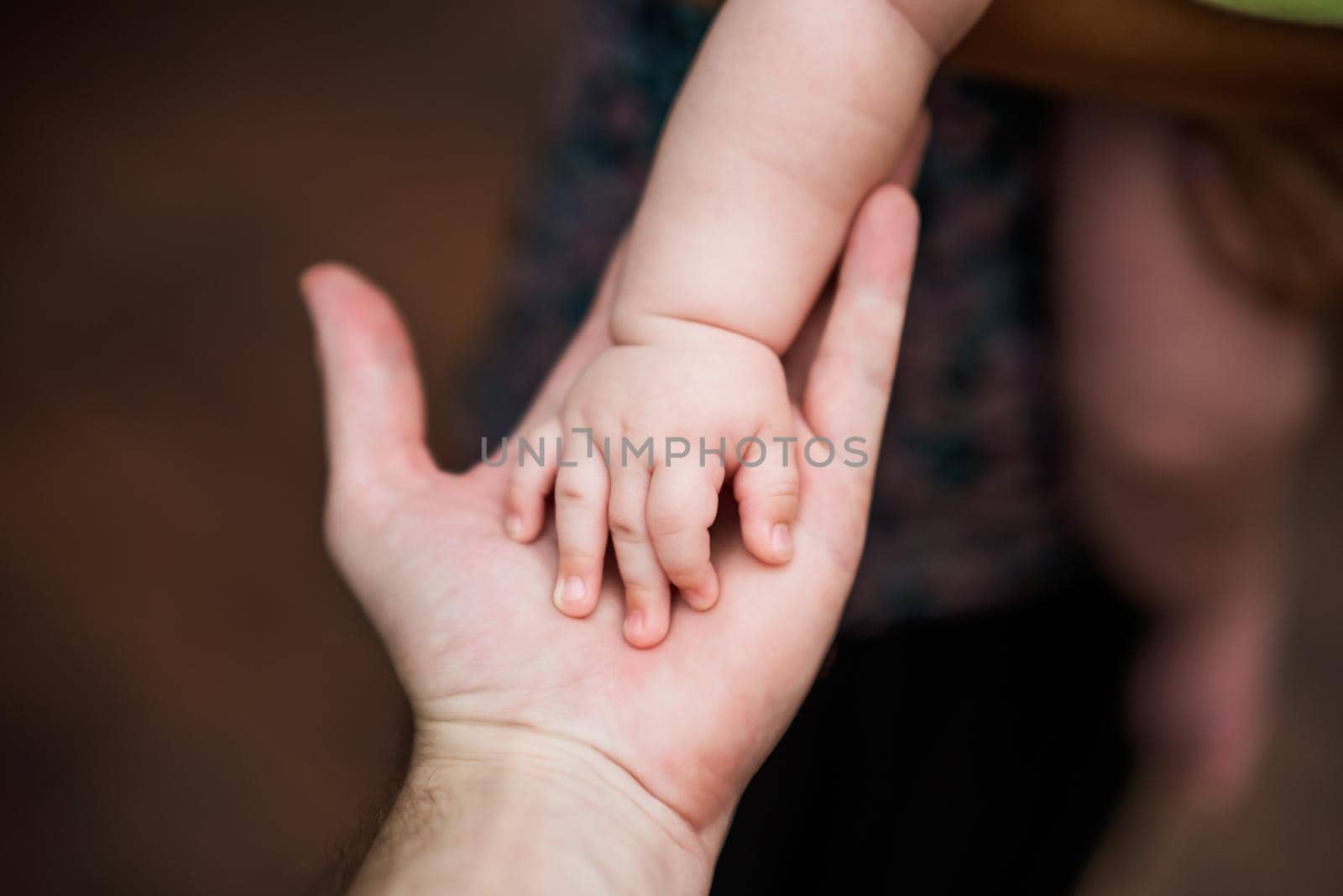 Close up image of  father's   and his baby boy son hands holding each other. Focus on fingers.