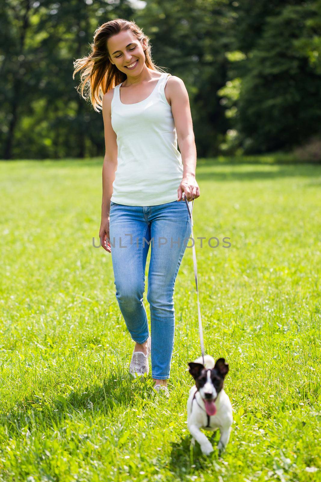 Beautiful woman enjoys walking with her cute dog Jack Russell Terrier in the nature.