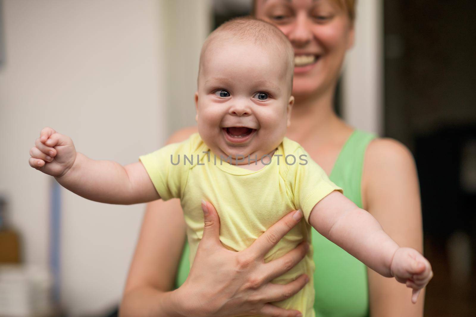 Mother enjoys holding her little cheerful baby boy.