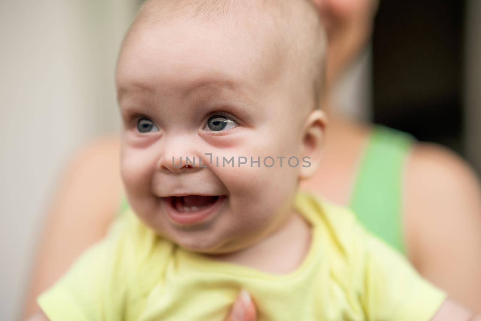 Mother enjoys holding her little cheerful baby boy.