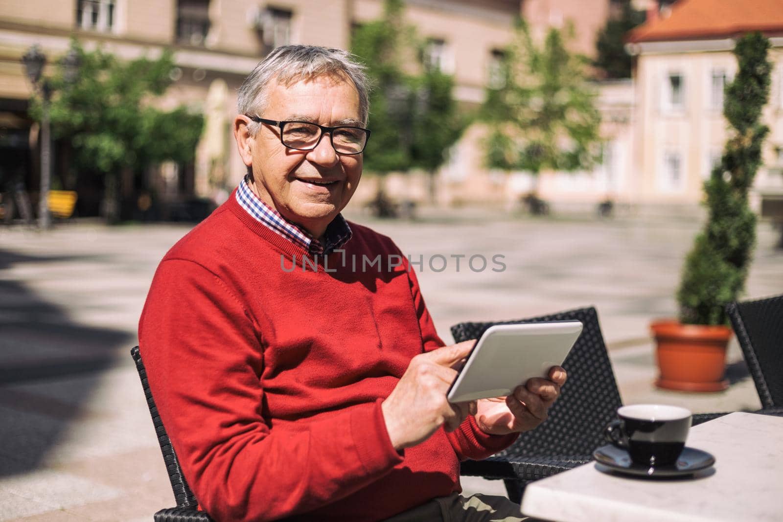 Senior man using digital tablet while drinking coffee at the bar.Image is intentionally toned.