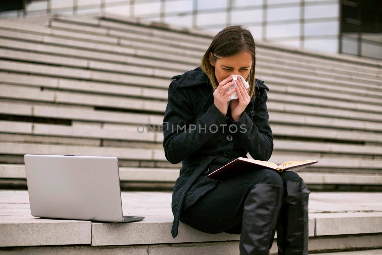 Businesswoman blowing nose while working by Bazdar
