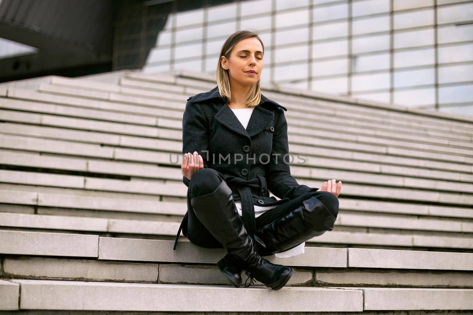 Beautiful businesswoman enjoys meditating outdoor.