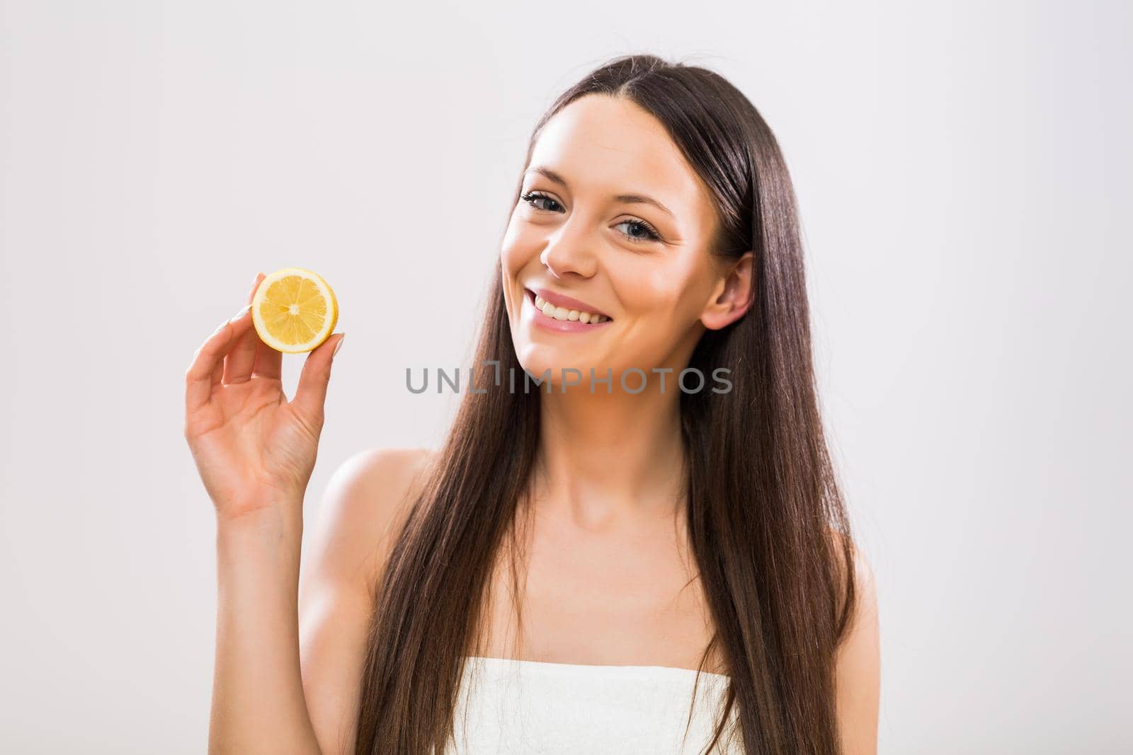 Beautiful brunette woman holding slice of lemon.