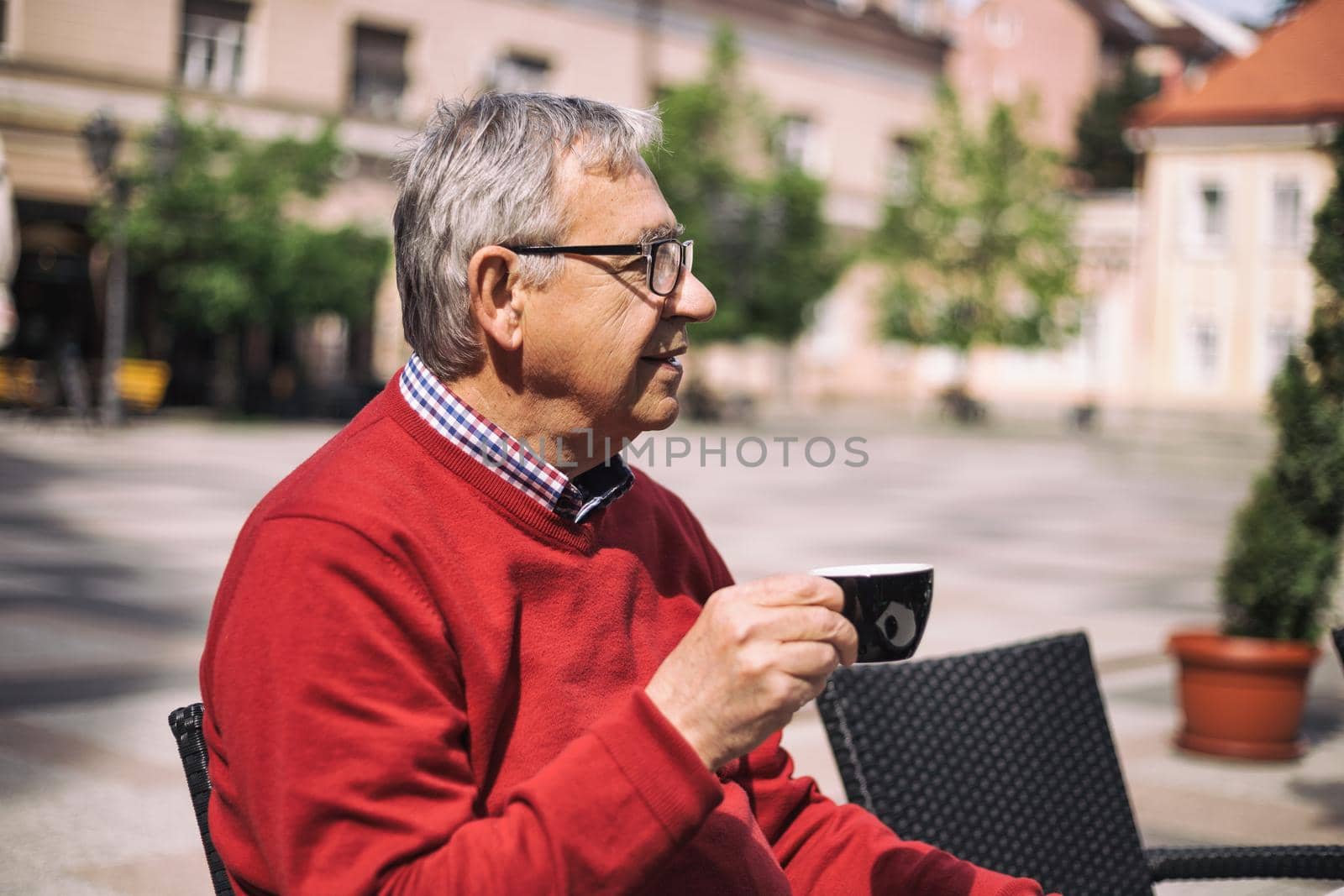 Cheerful senior man enjoys drinking coffee at the bar.Image is intentionally toned.
