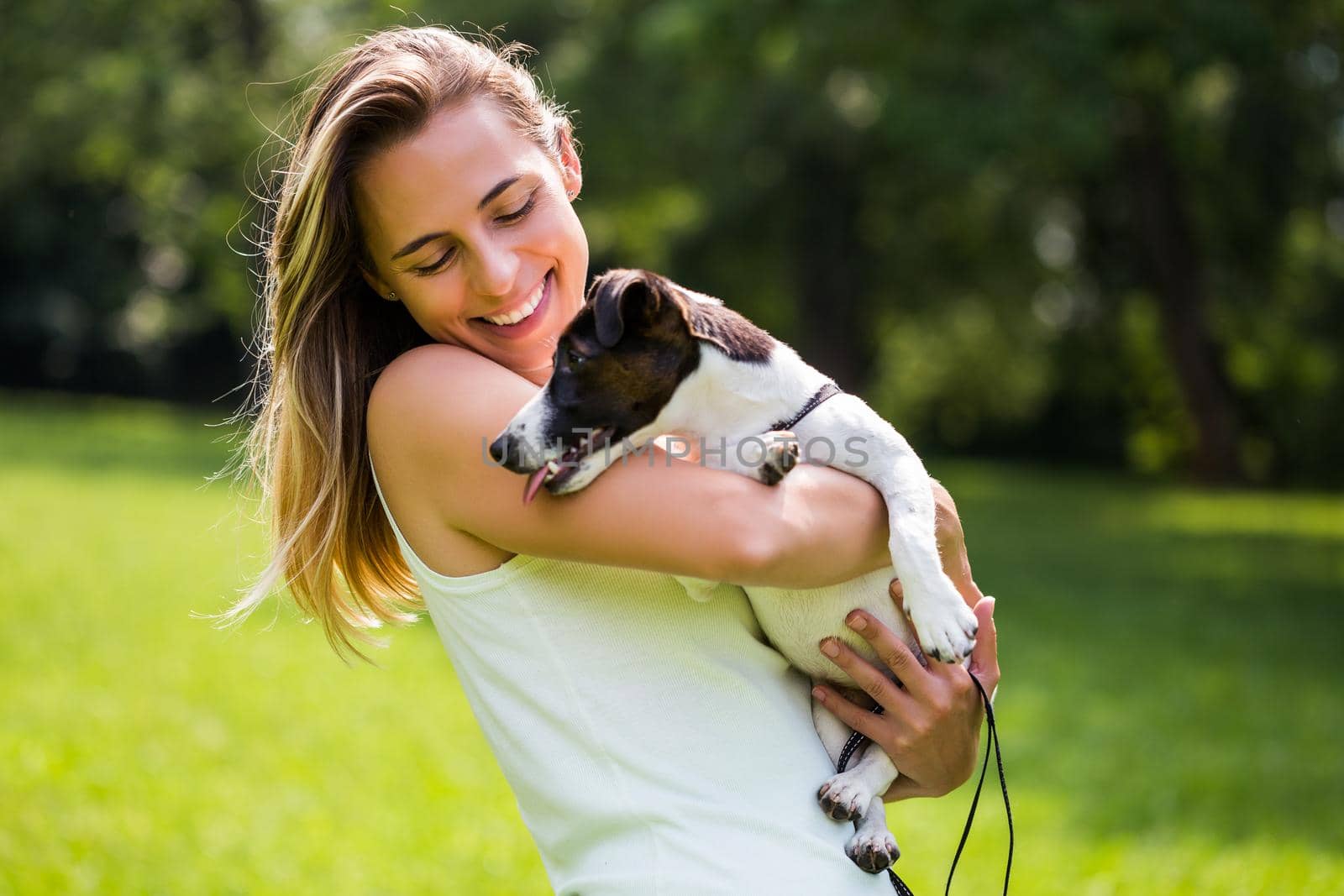 Beautiful woman enjoys spending time in the nature with her cute dog Jack Russell Terrier.