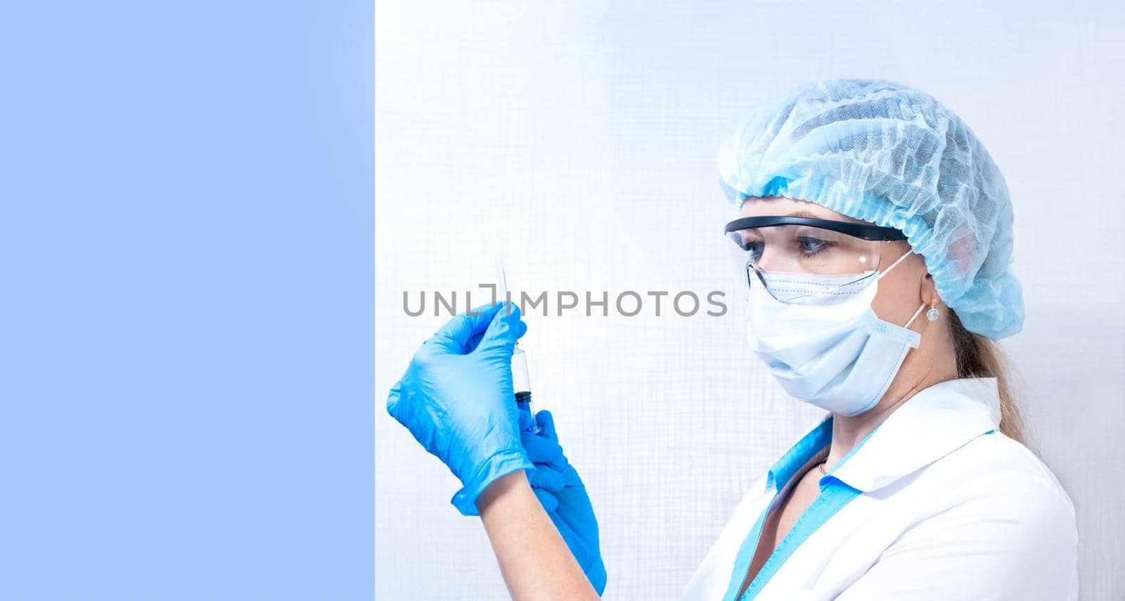 nurse in mask, hat and glasses holds a syringe with medicine by levnat09