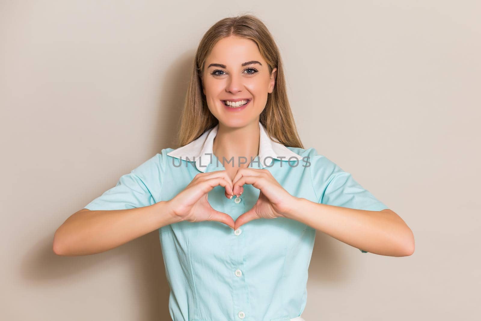 Portrait of medical nurse showing heart shape with hands.