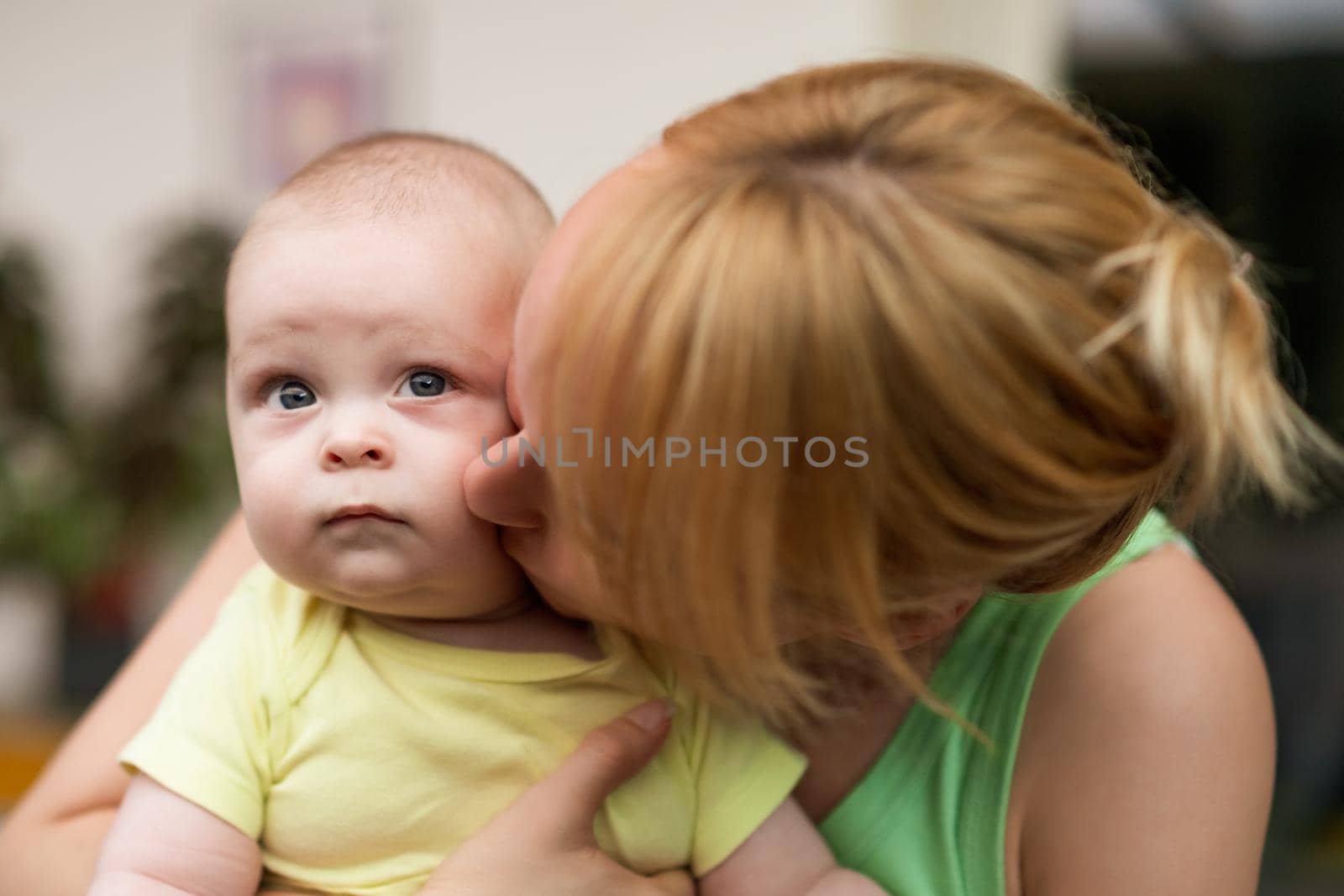 Mother enjoys holding and kissing her little cheerful baby boy.